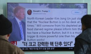 People watch a TV news program showing the Twitter post of U.S. President Donald Trump while reporting North Korea's nuclear issue at Seoul Railway Station in South Korea on Wednesday. Trump boasted that he has a bigger and more powerful "nuclear button" than North Korean leader Kim Jong Un does, but the president doesn't actually have a physical button. The letters on the screen read: "More powerful nuclear button." (AHN YOUNG-JOON / AP)