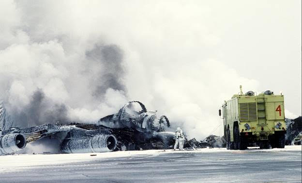 A crash crewman sprays a foam/water agent on an Alaska Air National Guard KC-135E Stratotanker aircraft that exploded and burned while taxiing to a parking area. Eielson AFB, Alaska