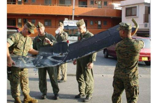 U.S. soldiers carry debris from a crashed Marine helicopter in the city of Ginowan, Okinawa Prefecture, on Aug. 13, 2004. The helicopter crashed into Okinawa International University, injuring three crew members.