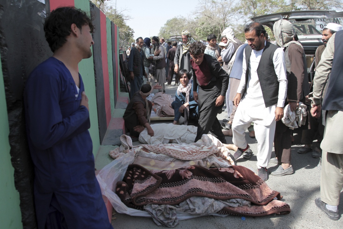 Afghan villagers stand over bodies of civilians during a protest