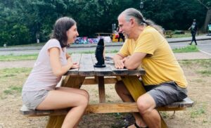 Timi Barabas and Marc Eliot Stein recording podcast episode at a picnic table in Prospect Park, Brooklyn