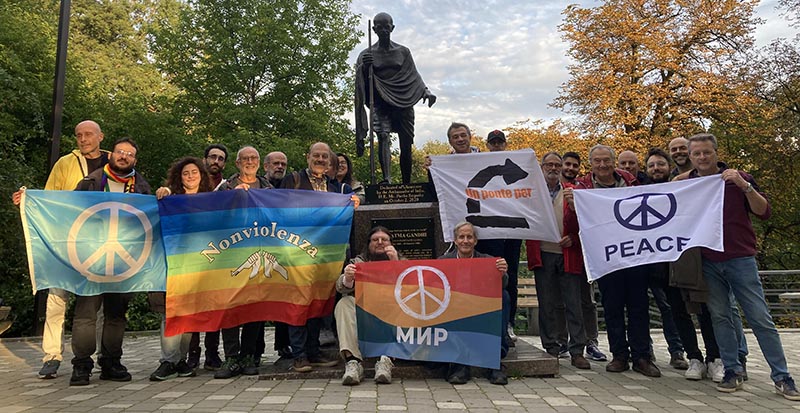 Peace activists including Yurii Sheliazhenko and John Reuwer (center) hold peace signs in front of the Gandhi statue in Kyiv, Ukraine