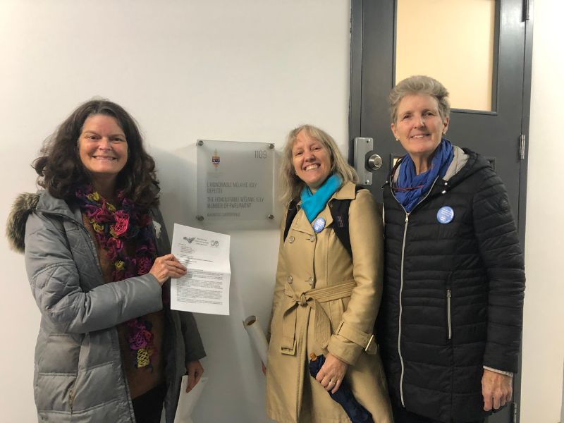 Louise Royer, Cym Gomery and Sally Livingston pose with our letter, outside of Mélanie Joly's office