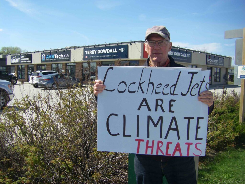 WBW Chapter member Frank stands outside MP office with sign reading Lockheed Jets are Climate Threats