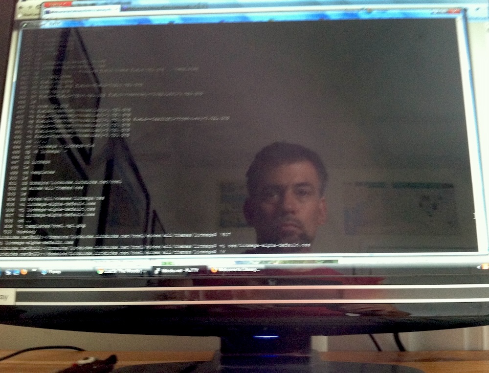 The author's face reflected on a computer screen showing a terminal window.